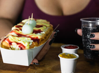 holding-in-her-hands-a-hot-dog-with-sauces-cheese-2025-03-10-06-38-55-utc