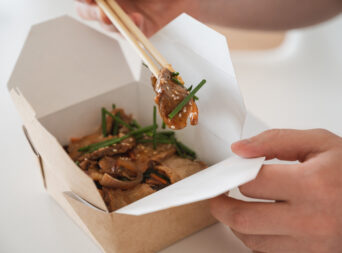 unrecognizable man eating poke bowl with ducke and rice